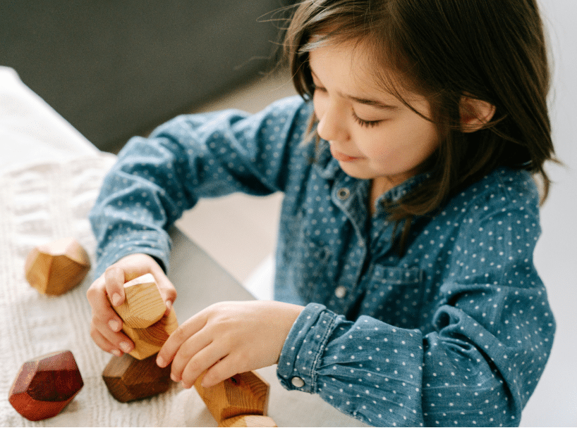 Young girl plays with and stacks educational toys