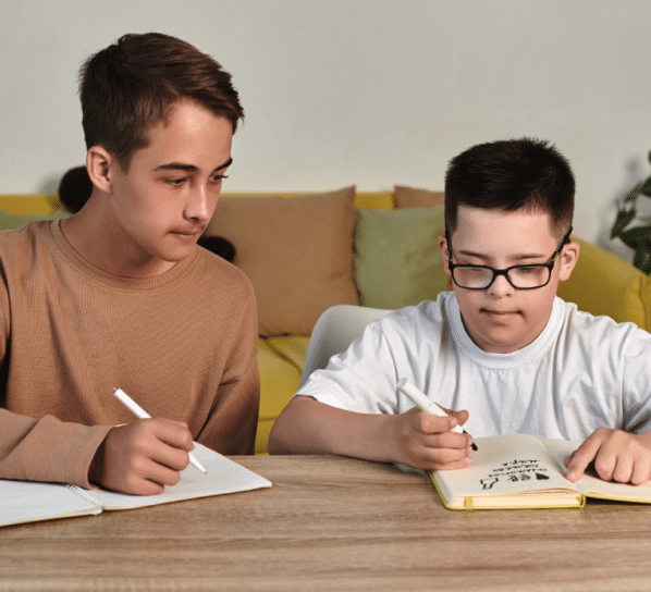 An older student mentors and teaches a younger student